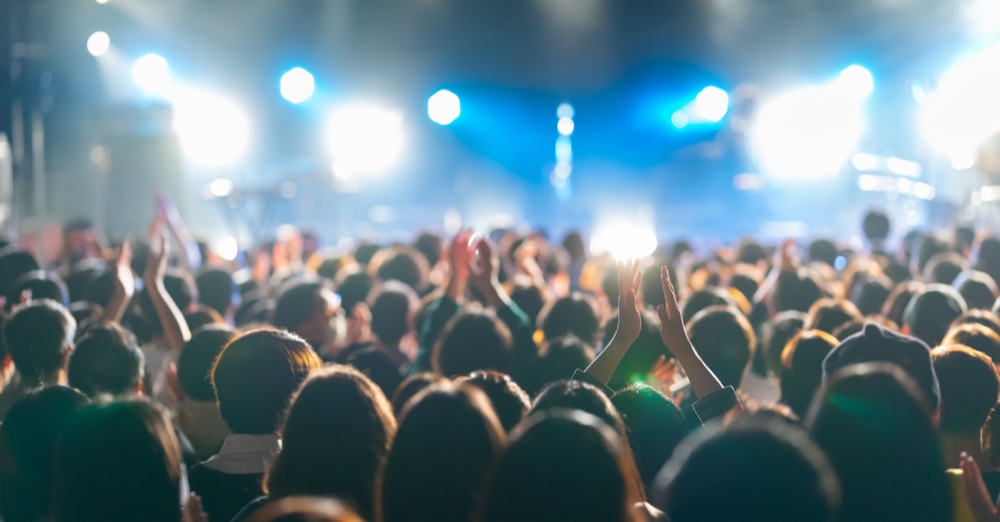 ステージの照明に照らされたライブ会場で拍手する観客